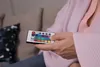 A person's hands holding a remote control with colored buttons. Anteprima dell’immagine prodotto