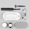 A flat lay of personal grooming and accessory items on a light gray background. Voir les images du produit