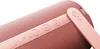 A close-up view of a coral red Loewe WE. Hear 2 Bluetooth speaker, showing the control buttons and a strap with the brand logo. Produktbild-Vorschau