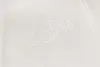 A close-up of a white textured fabric with embroidered text. Produktbild-Vorschau