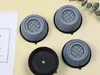 Four anti-vibration pads for a washing machine are laid out on a light yellow surface, with a piece of paper and some greenery in the background. Voir les images du produit