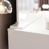 A close-up view of a white vanity table with a mirror and a candle. Voir les images du produit