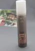 A bottle of Wella EIMI Natural Volume hair product is shown in the foreground, with a blurred image of a person in the background. Podgląd zdjęcia produktu