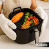 A person wearing oven mitts holds an air fryer basket containing salmon and vegetables. Náhled obrázku produktu