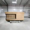 A wooden reception desk with a black metal mesh insert is shown in a warehouse or large empty room. Produktbild-Vorschau