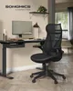 A black ergonomic office chair is placed next to a black standing desk with a computer monitor, lamp, and desk accessories. Produktbild-Vorschau