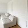 A corner of a room with a white sofa and white wall molding. Produktbild-Vorschau