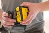 A person is holding a yellow and black Stanley laser level. Produktbild-Vorschau