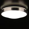 A close-up shot of a modern, circular ceiling light fixture with a brushed aluminum trim and a white diffuser. Produktbild-Vorschau