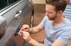 A man is using a dent repair tool on a car door. Produktbild-Vorschau