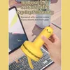 A hand holding a yellow chick-shaped mini vacuum cleaner over a keyboard, with a tablet in the background. Produktbild-Vorschau