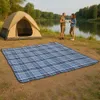 A couple is enjoying a picnic by a lake with a tent set up. Anteprima dell’immagine prodotto