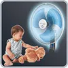 A baby playing with a teddy bear next to a fan. Produktbild-Vorschau