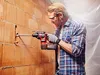 A man is using a cordless rotary hammer drill to make a hole in a brick wall. Produktbild-Vorschau