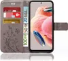 A grey flip phone case with a floral design, showing credit cards and euro banknotes inserted into the card slots, and a smartphone displayed within the case. Produktbild-Vorschau