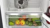 Close-up view of a refrigerator drawer filled with fresh fruits and vegetables, with a metal pot on the shelf above. Voir les images du produit