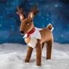 A plush reindeer toy standing in snow with a snowy blue background. Produktbild-Vorschau