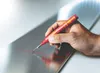 A hand holding a red marker with a laser line on a metal surface. Produktbild-Vorschau