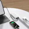 A white power bank is charging a laptop, a smartphone, and a pair of wireless earbuds on a white table. Produktbild-Vorschau