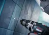 A person is using a cordless drill to drill a hole in a tiled wall. Podgląd zdjęcia produktu
