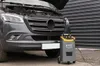 A car battery charger is connected to a vehicle with its hood open. Produktbild-Vorschau