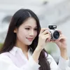 A woman is holding a camera and taking a picture. Podgląd zdjęcia produktu