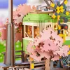 A close-up of a 3D wooden model of a train station with a tram and cherry blossom trees. Produktbild-Vorschau