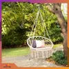 A macrame hammock chair with a pillow hanging from a tree branch in a garden setting. Produktbild-Vorschau