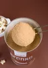 A scoop of brown sugar is being taken from a tin labeled "Xucker Bronxe". Produktbild-Vorschau
