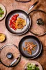 A top-down view of two YEZEY frying pans on a wooden table, one with salmon and tomatoes, the other with fries, with lids nearby. Náhled obrázku produktu
