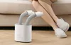 A person wearing slippers is sitting on a couch next to a shoe dryer. Produktbild-Vorschau