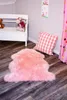 A pink sheepskin rug is placed on a wooden floor in a child's room, next to a white bench with stuffed animals and a pink gingham pillow. Produktbild-Vorschau