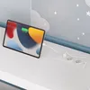 A tablet is charging on a white desk next to a wall with cloud and star decorations. Produktbild-Vorschau