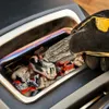 A gloved hand is adding charcoal to a grill. Produktbild-Vorschau