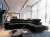 A modern living room with a large black sectional sofa, coffee table, and stairs leading to an upper level. Large windows with sheer curtains are visible in the background. Produktbild-Vorschau