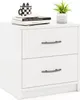 A white nightstand with two drawers is shown against a white background. There are books and a plant on top of the nightstand. Podgląd zdjęcia produktu