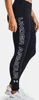 A person wearing black leggings with white lettering on the side, and white sneakers. Produktbild-Vorschau