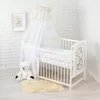 A white crib with bedding, a canopy, a teddy bear, and a small rug. Anteprima dell’immagine prodotto