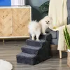 A small dog is standing on a set of pet stairs next to a chair and a cabinet. Produktbild-Vorschau
