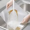 Hands washing a textured mat under running water in a sink. Voir les images du produit