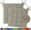 Two beige outdoor seat cushions with ties and tufting, shown on a white background. A circular inset highlights water droplets on the fabric.