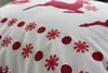 A close-up view of a white fabric with a repeating pattern of red snowflakes and reindeer. Podgląd zdjęcia produktu