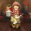 A Christmas-themed figurine of a girl holding a lantern and a reindeer, set against a fireplace background. Produktbild-Vorschau