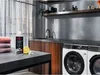 A laundry room setting with a washing machine, sink, and various items on a countertop. Produktbild-Vorschau