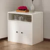 A white cabinet with two doors and an open shelf above, decorated with cups and a plant. Produktbild-Vorschau