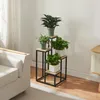 A plant stand with multiple plants is placed next to a sofa in a living room. Náhled obrázku produktu