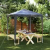 A party tent set up in a garden with a picnic table and benches. Podgląd zdjęcia produktu