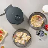 A dark gray waffle maker is placed on a gray surface next to plates of waffles and bowls of berries. Anteprima dell’immagine prodotto