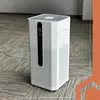 A white air purifier sits on a patterned carpeted floor. Náhled obrázku produktu