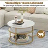 A round coffee table with a cat sleeping in a bed underneath it, placed in a living room setting with a sofa in the background. Produktbild-Vorschau